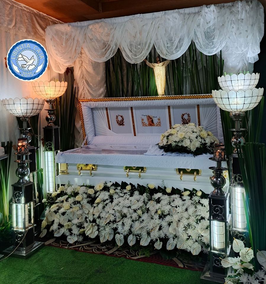 Wake setup prepared by Libintia Caja Mortuary Care with white drapes, capiz lamps and white flowers around the casket